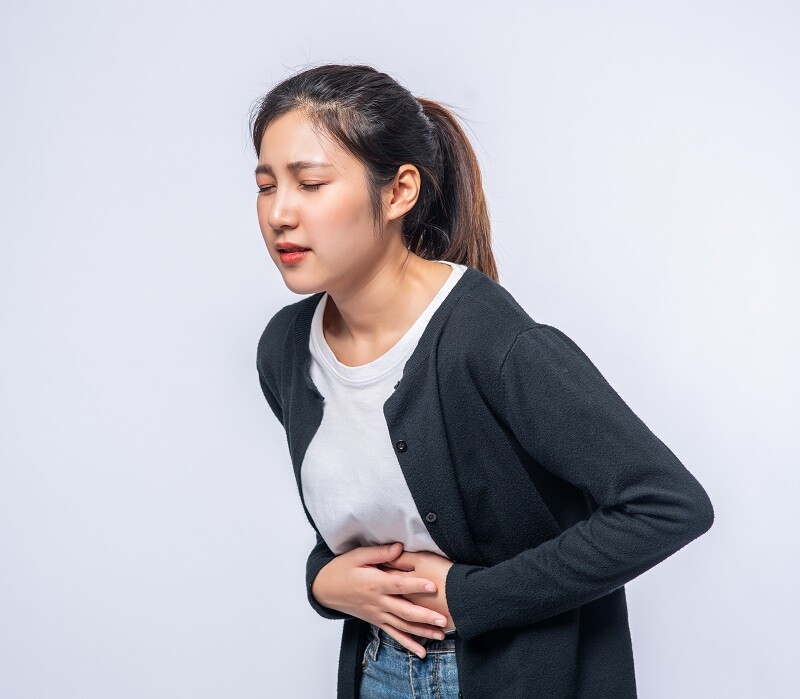 A Woman Standing With A Stomach Ache And Presses Her Hand On Her